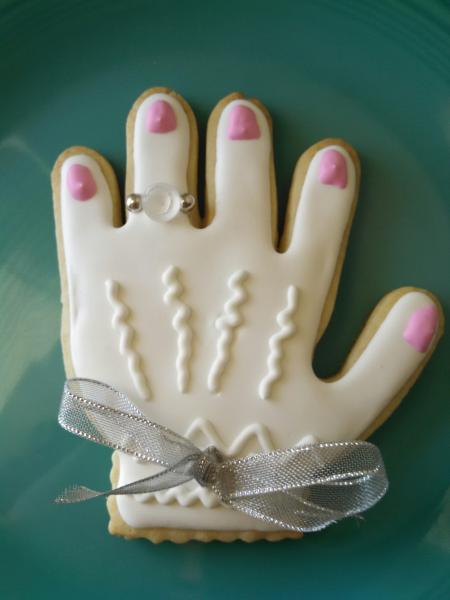The sugar cookie is decorated with a sugar diamond and ribbon to match the wedding colors.